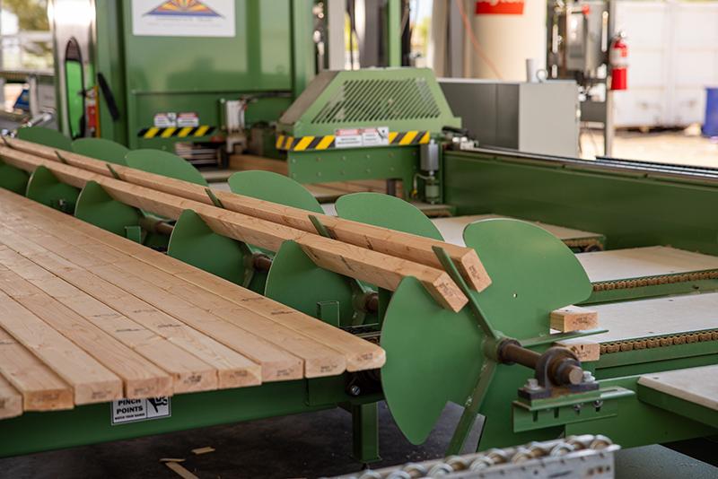 Close-up of lumber automatically feeding from the loading table into the Monet Linear Saw.